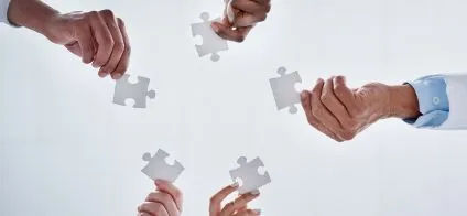 Cercle de personnes reliant des pièces de puzzle, symbolisant la collaboration.