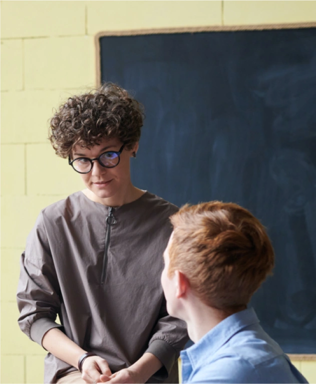 Two colleagues having a focused conversation in front of a chalkboard in a creative office space.