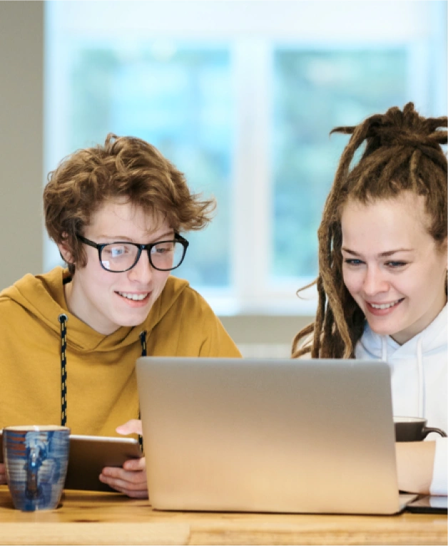 Two young professionals collaborating and looking at a laptop screen together during a work session.