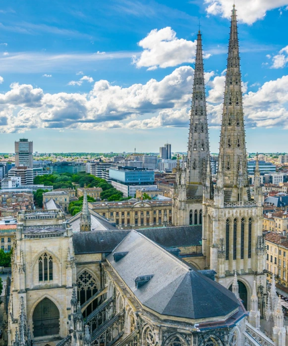 Vue en hauteur de la cathédrale gothique Saint-André de Bordeaux, un monument emblématique de la ville souvent mis en avant par une agence SEO Bordeaux, avec ses deux flèches imposantes se détachant sur un ciel nuageux.