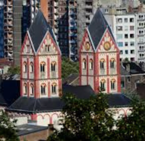 Vue rapprochée des tours jumelles romanes de la collégiale Saint-Barthélemy, célèbres pour leurs motifs géométriques rouges et blancs, une icône du patrimoine local que l'on pourrait retrouver sur le site d'une agence SEO Liège soucieuse de son ancrage local.