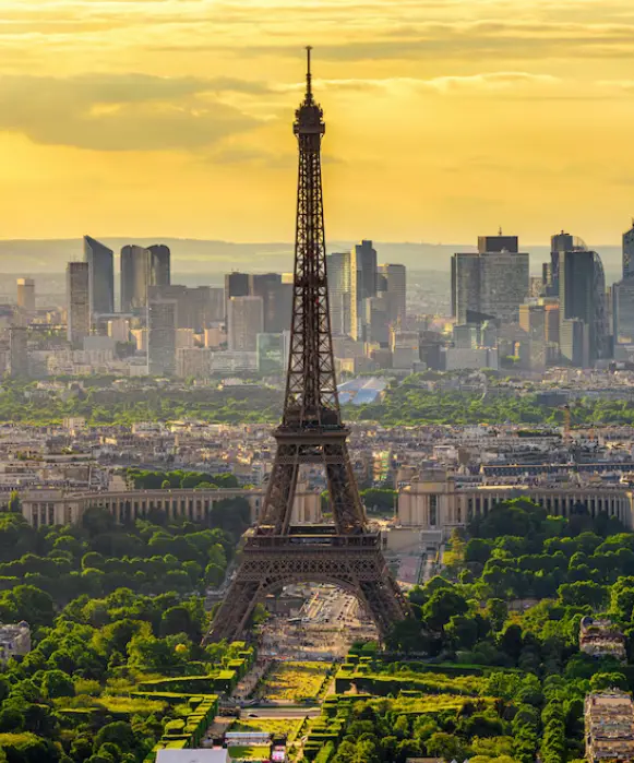 Vue panoramique en hauteur de la tour Eiffel à l'heure dorée surplombant le Champ de Mars et La Défense.