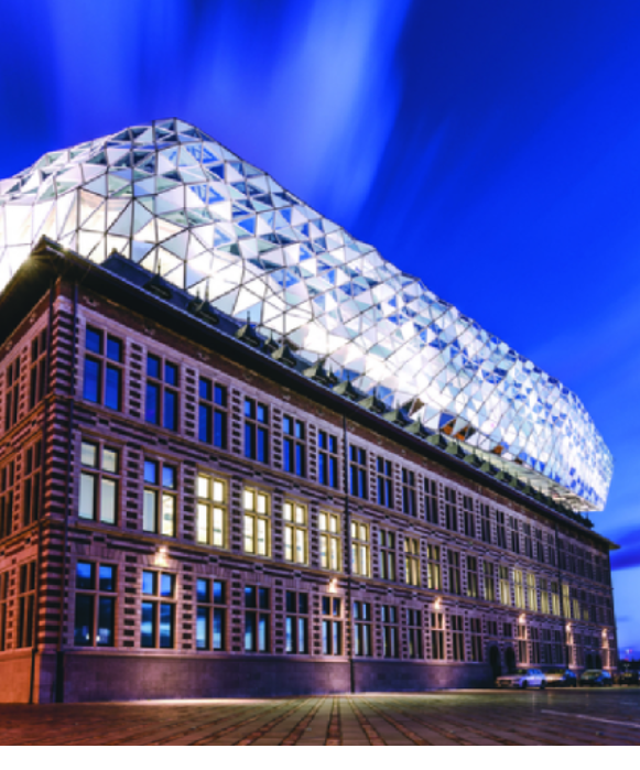 L'impressionnante Maison du Port conçue par Zaha Hadid la nuit, où une structure de verre futuriste en forme de diamant surmonte une ancienne caserne de pompiers restaurée.