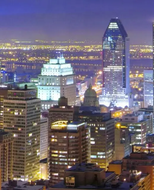 Une vue nocturne vibrante de la silhouette du centre-ville de Montréal, mettant en vedette des gratte-ciel illuminés et l'édifice Sun Life sous un ciel violet profond.