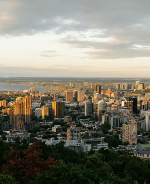 Une large prise de vue aérienne de la ville à l'heure dorée, avec la lumière du soleil se reflétant sur les bâtiments sous un ciel nuageux.