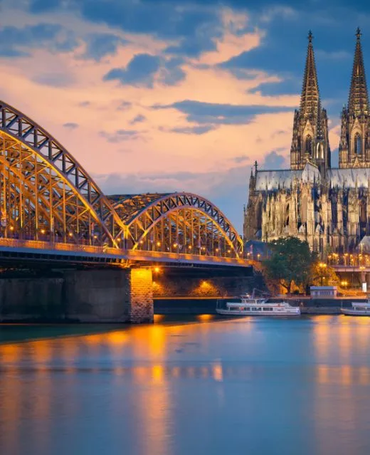 La majestueuse cathédrale de Cologne et le pont Hohenzollern illuminés le soir.