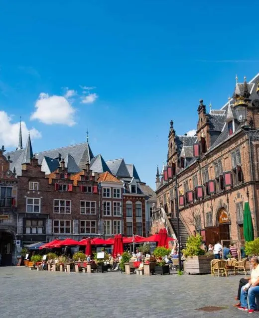 Terrasse de café animée sur une place historique pavée aux Pays-Bas.
