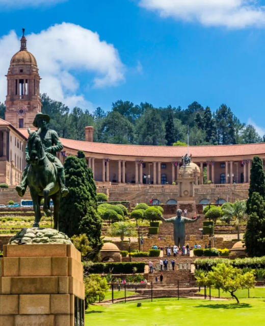 Jardins en terrasses et statues des Union Buildings de Pretoria en journée.