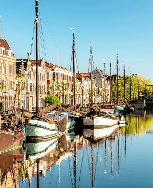 Vieux bateaux traditionnels amarrés le long d'un canal bordé de maisons.
